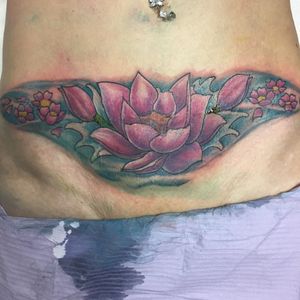 Cover up de cicatrice de césarienne. Lotus néo trad, ou néo traditionnel en couleur sur le bas du ventre d'une femme. Lotus fuschia et eau turquoise.