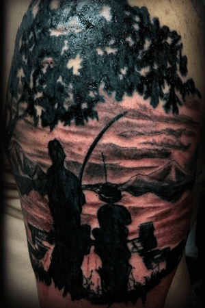 Père et son fils à la pêche sur le bout du quai assis en silhouettes avec un arbre et des montagnes