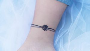 A purple knotted bracelet around the ankle.#tattoo #Korea #tattooart #koreatattoo #koreatattooist #flowertattoo #illustration #birthflowertattoo #tattooistartmag #hongdae #flowers #coloredtattoo #anklebracelet #watercolortattoo #hongdaetattoo #norigae #tattooistsion 