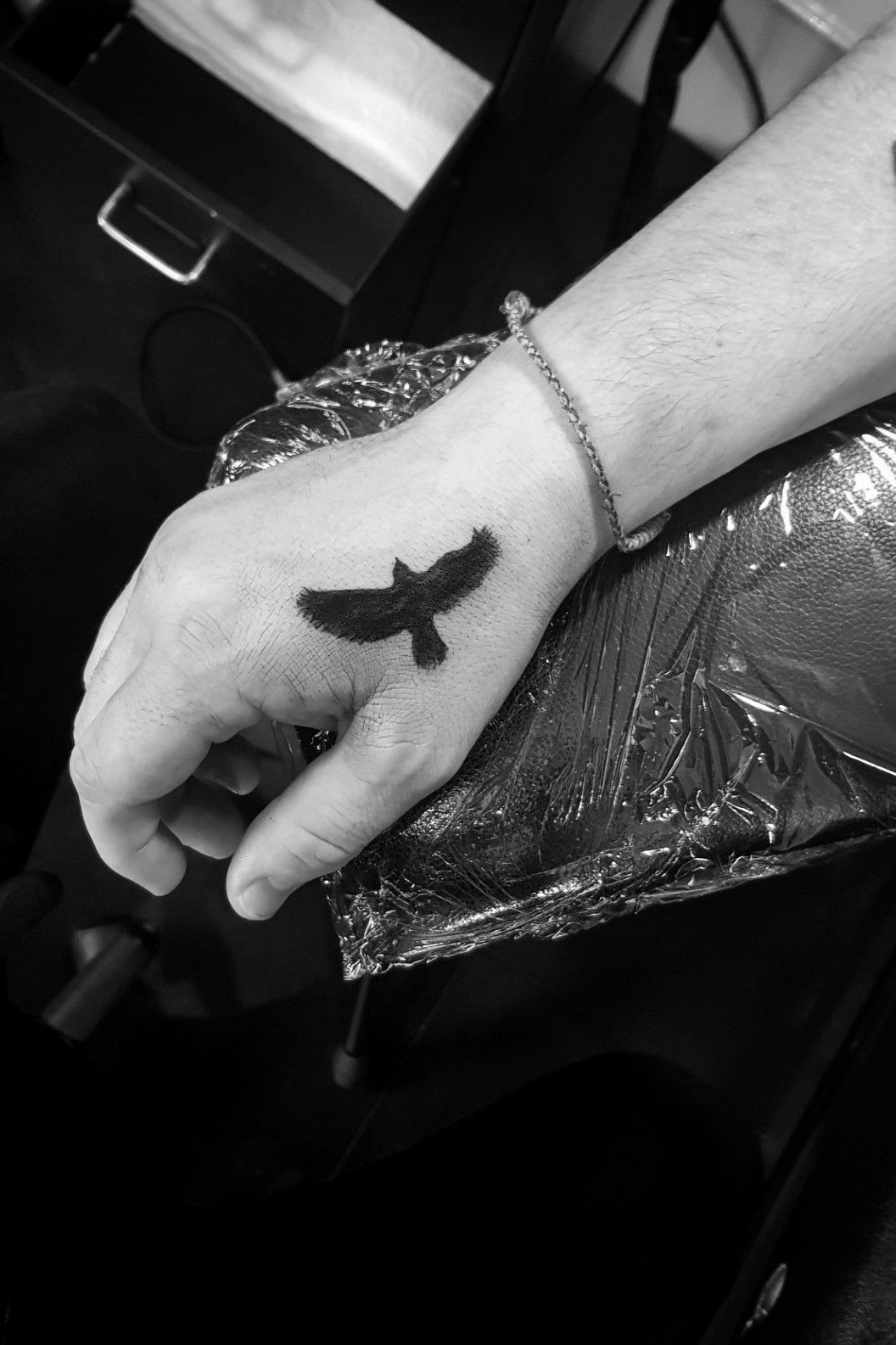 Initials and crow tattooed on the wrist minimalistic