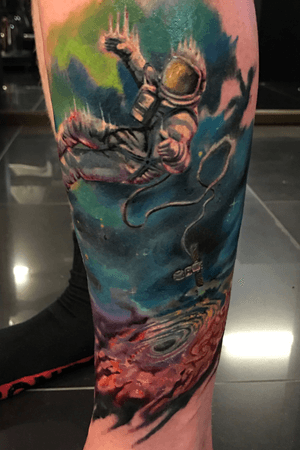 Space themed tattoo with astronaut and black hole 