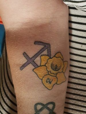 This is the 4th tattoo I had gotten.I had gotten it for my grandmother as we are so close, shes my best friend and i wanted to get something done for her.It's the sagittarius symbol which is her star sign and a daffodil as it's her favourite flower and her initials.It's also my first ever colour tattoo.