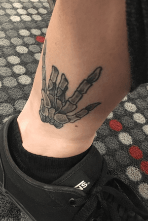 Ankle tattoo, skeleton hand means “I love you” in sign language