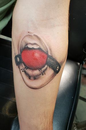 Woman's pierced mouth with ball gag. Lays on my inner forearm right after the elbow joint.