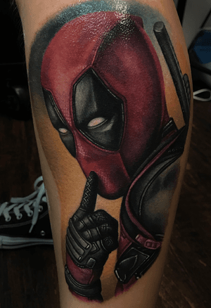 Realistic portrait of deadpool, tattooed on the lower leg.