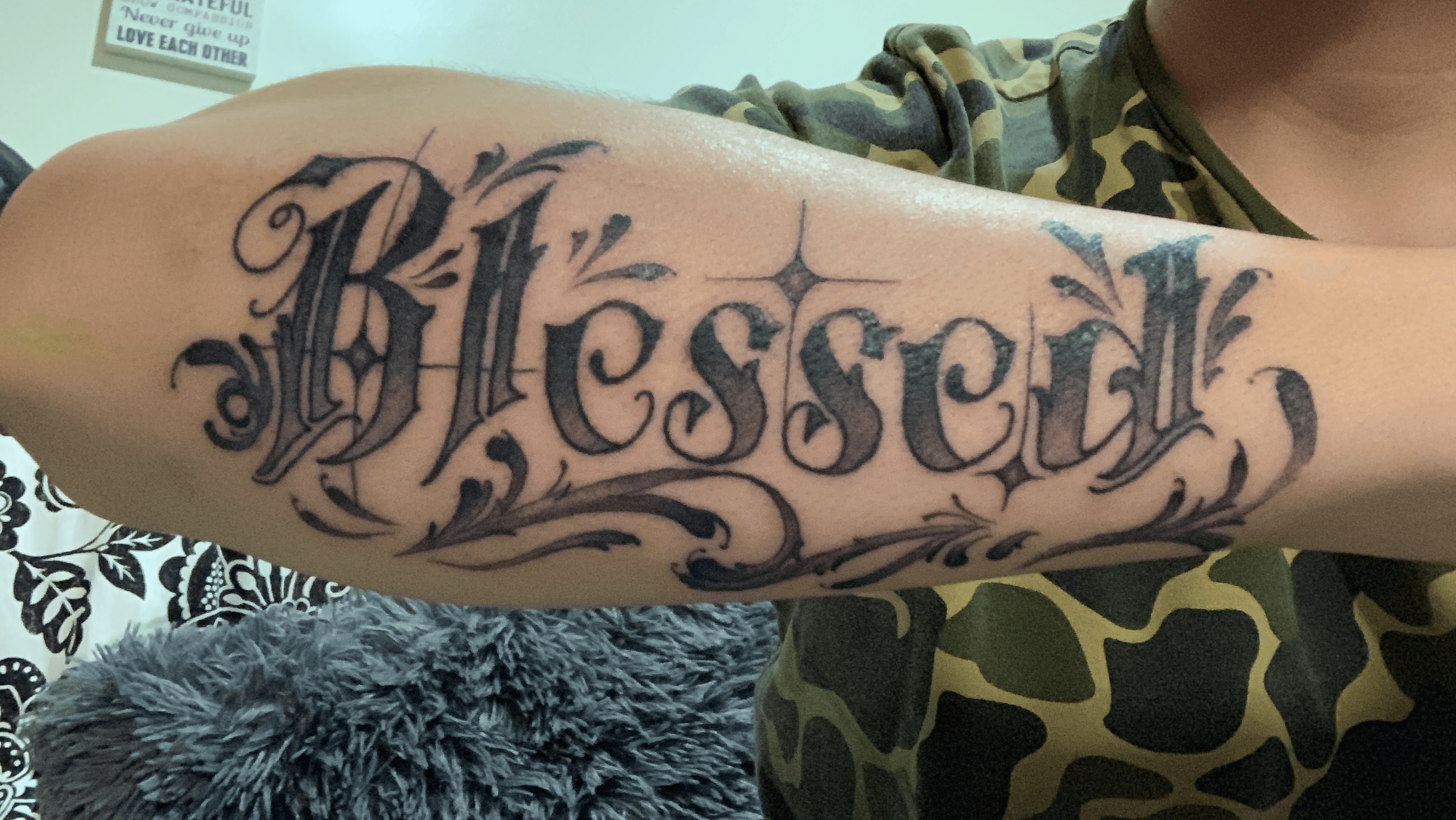 Lettering tattoo saying Blessed on the right forearm