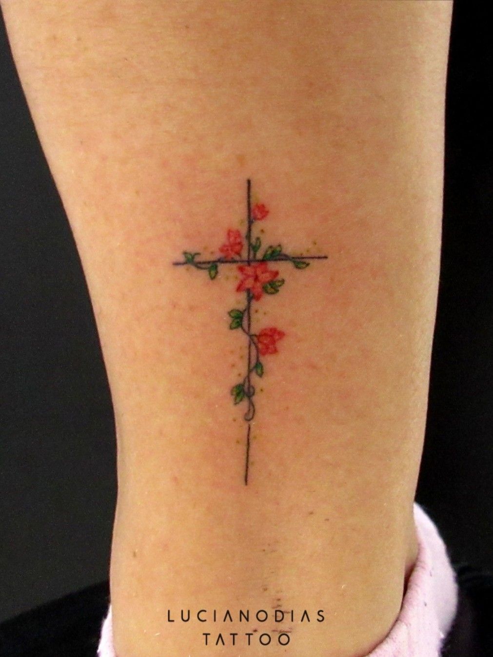Fine line flower cross tattoo on the wrist