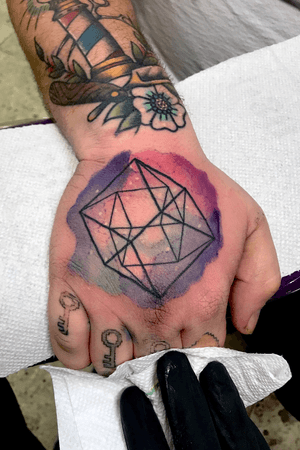 Water color universe looking tesseract logo on a hand
