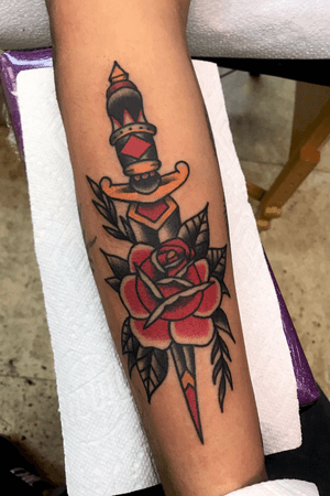 Traditinal dagger on rose on the back of a forearm 