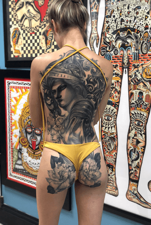 Stunning blackwork piece combining flower, woman, filigree, and helmet in an illustrative style on the back.