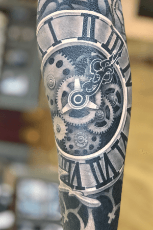 Black and grey clock on outside forearm of religeous sleeve.