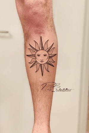 Experience the artistry of Patrick Bates with this illustrative blackwork sun tattoo on your shin. Striking and intricate design.