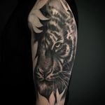 Black and white realism tattoo on arm of tiger hidden in the blossoms.