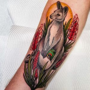 Kangaroo with VB beer can in pouch amongst grevilleas