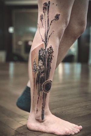 Blackwork design featuring a intricate tree and geometric pattern, done by La Bottega dell'Arte on the lower leg.