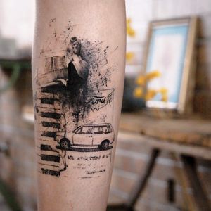 A striking blackwork tattoo featuring a piano, woman, car, and keyboard design by La Bottega dell'Arte. Perfect for music lovers!
