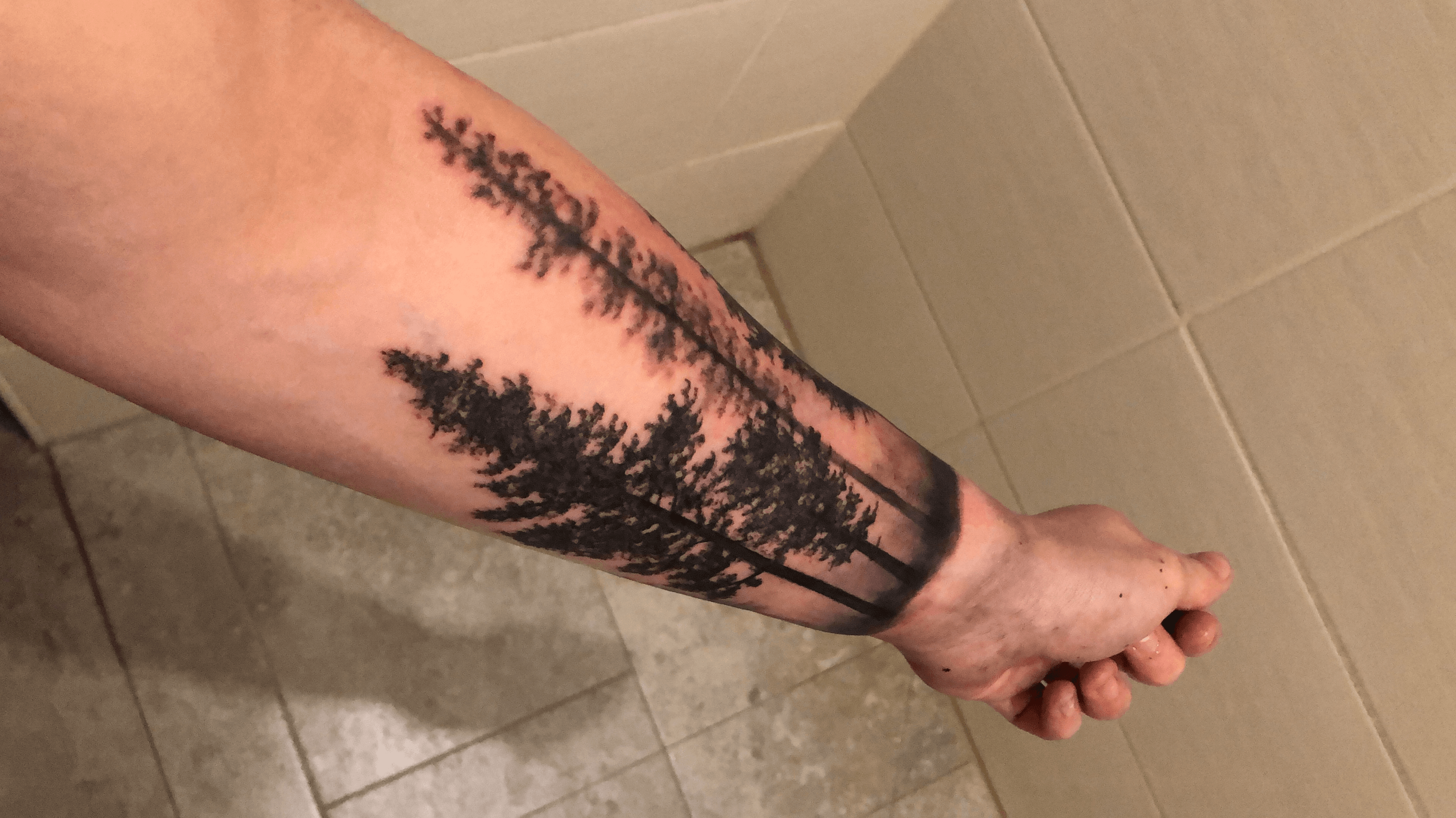 Pine tree forest tattoo on the left upper arm