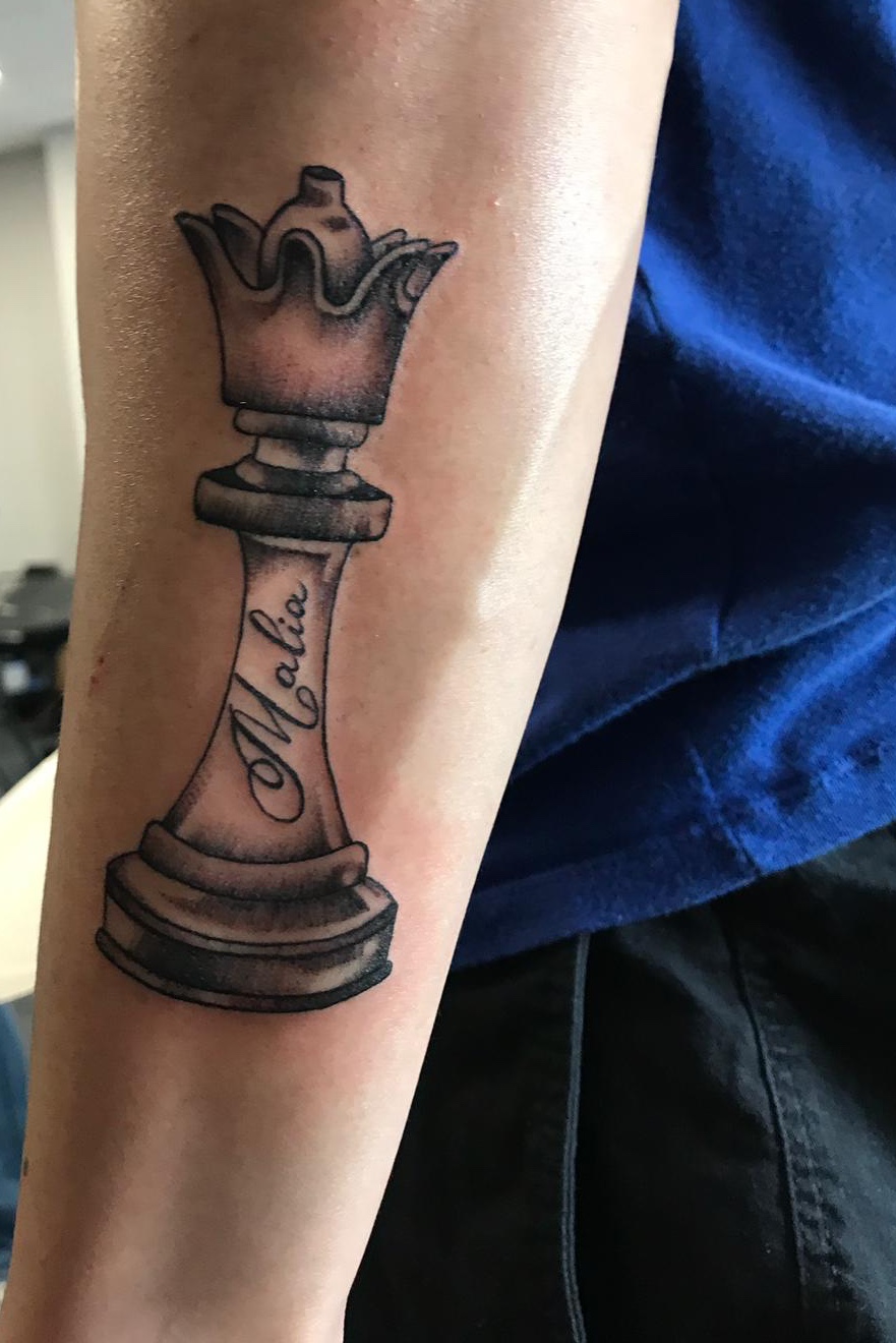 One line chess queen tattoo located on the inner arm.