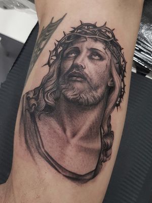 Get a stunning blackwork tattoo of Jesus on your upper arm by talented artist Dani Mawby. Perfect for devout believers seeking a unique design.