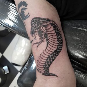 Bold and striking upper arm tattoo featuring a sleek blackwork snake design by Dani Mawby.