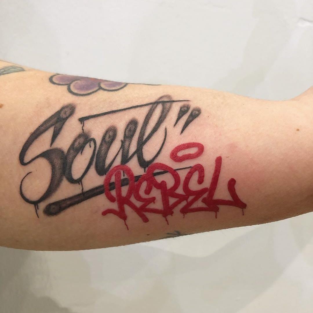 Tattoo of the word strength in red ink located on