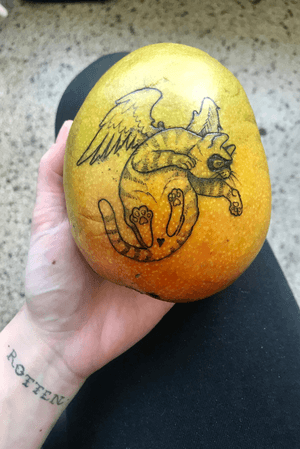 Funny original design tattoo by me on a mango. Style note: i love hiding spots with shapely “censor bars”, in this case a little heart. 