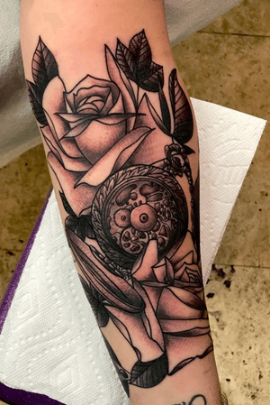 Black and grey roses with the inner workings of a fancy ass pocket watch.    Filling a forearm 