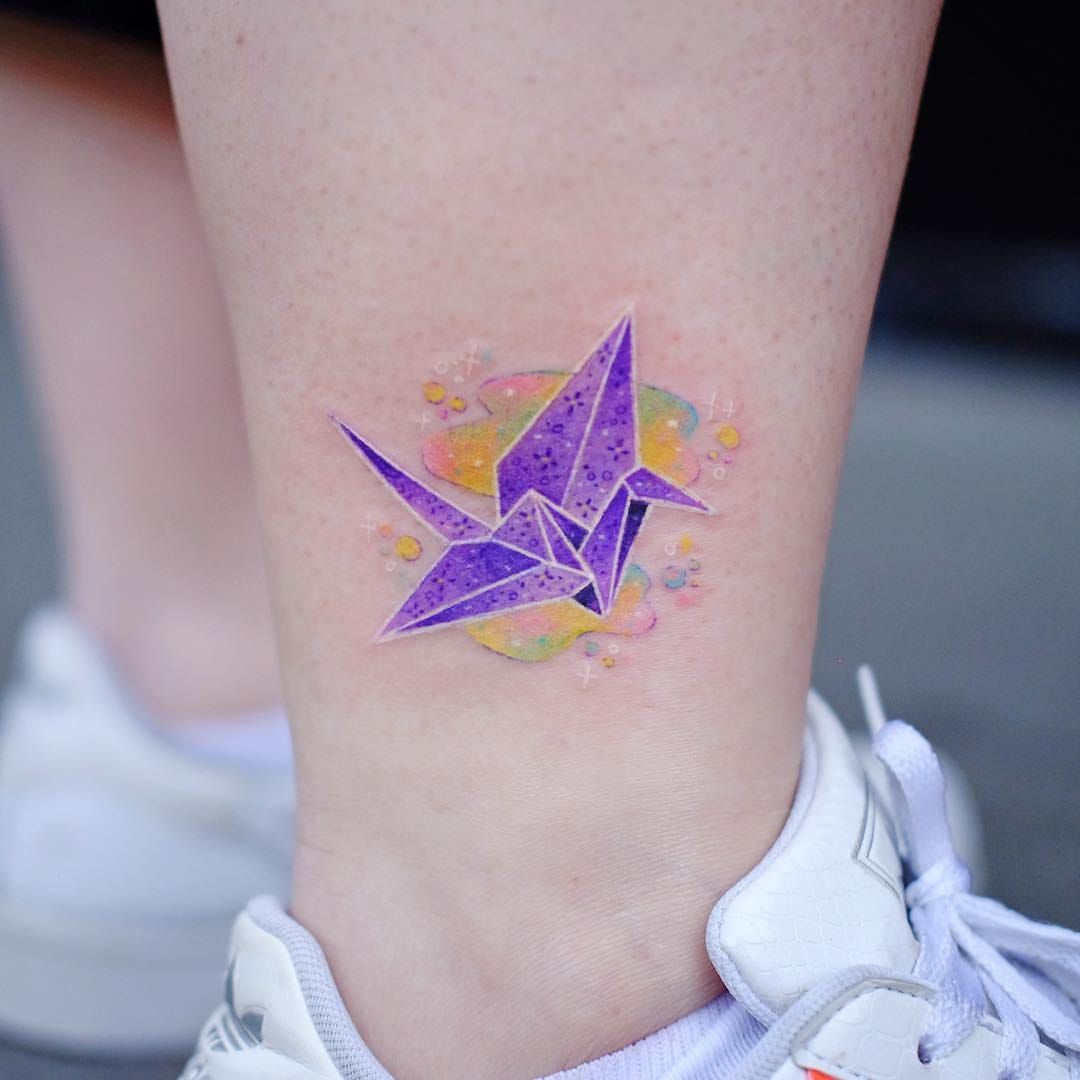 Origami crane tattoo on the left inner forearm