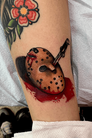 Little traditional jason mask with wet wet blood on a horror themed leg 