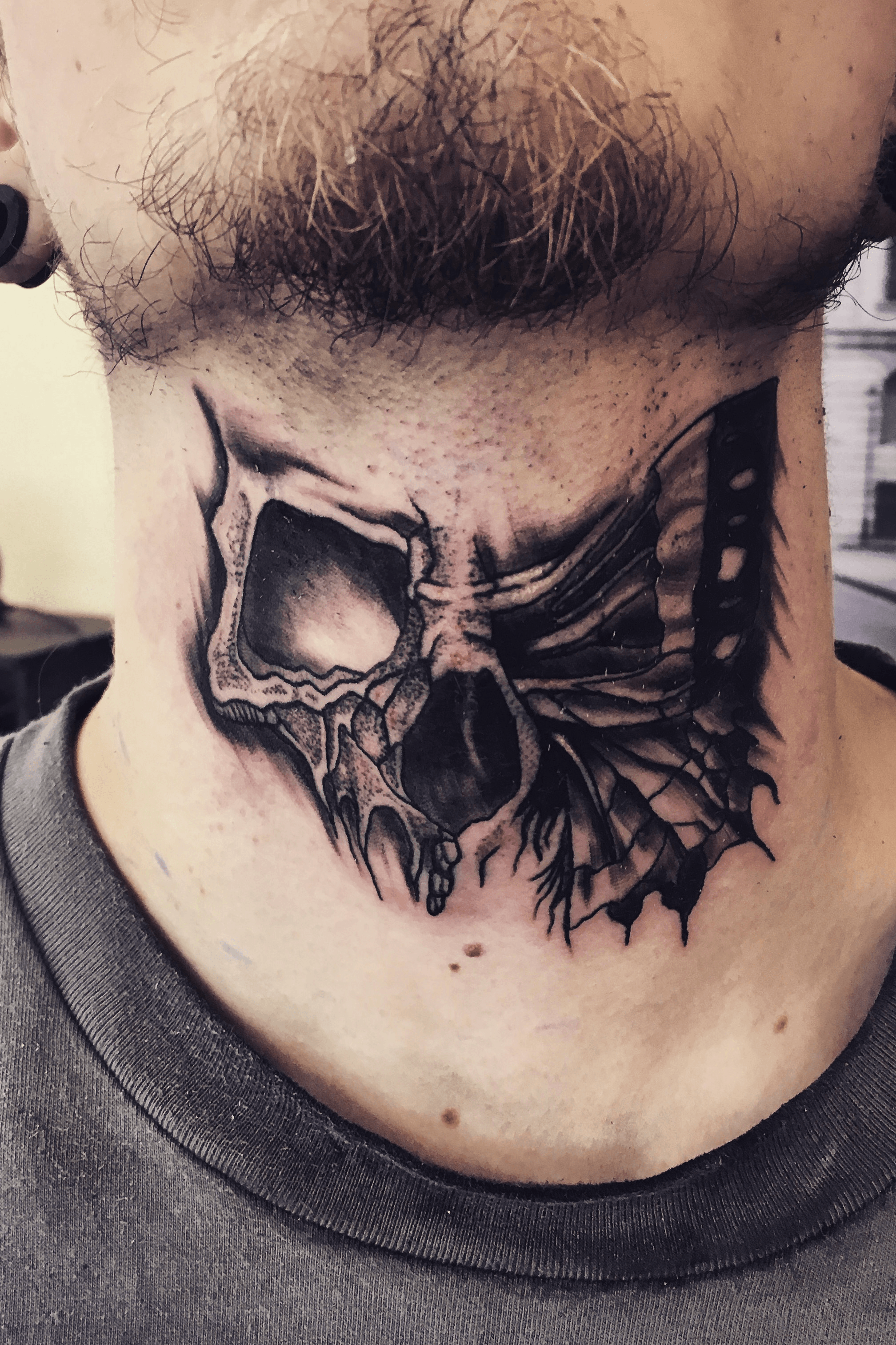 Half skull half butterfly front neck tattoo