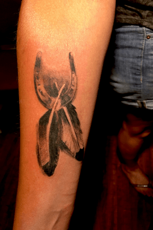 Horseshoe and feathers. Black and grey realism