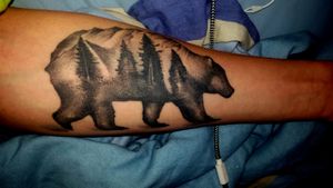 Brown Bear outline with a tree line and mountian range inside him/on its back.Own representation to the story of Atlas in Greek mythology