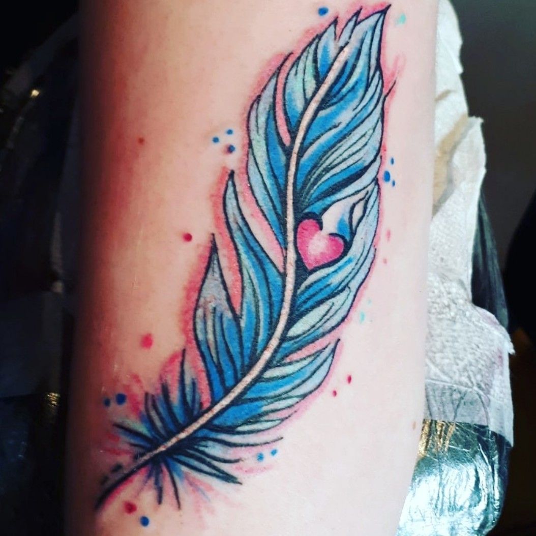Side tattoo of a grey and blue feather on Anne