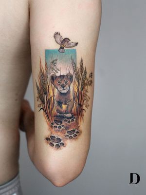Beautiful tattoo by Deborah Genchi #DeborahGenchi #debartist #realism #realistic #illustrative #watercolor #color #lioncub #babyanimal #animal #nature #cute #bird #lionking #pawprints #upperarm #arm
