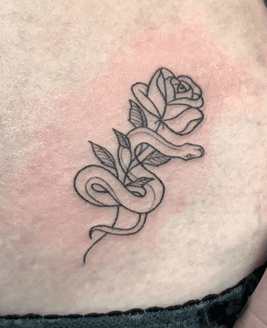 Exquisite fine line tattoo featuring a snake and flower motif, expertly crafted by Nikita Jade Morgan on the back.