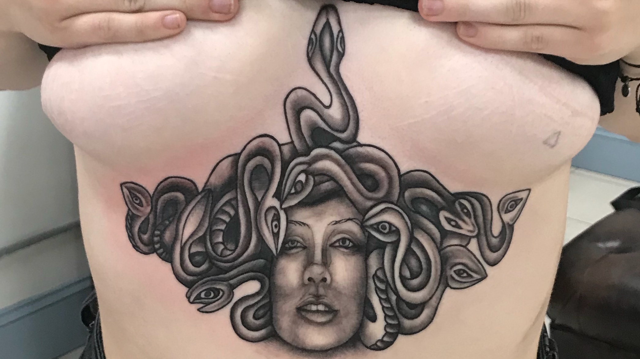 Medusa under breast tattoo