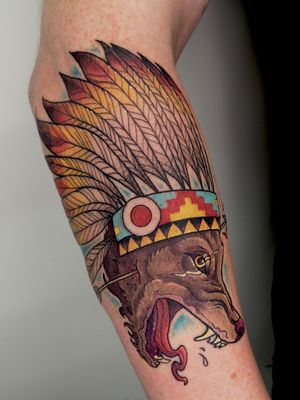 Adrian Suez creates a stunning neo-traditional tattoo featuring a fierce wolf surrounded by intricate warbonnets on the forearm.