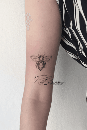 Get buzzed with this beautifully illustrated bee tattoo on your upper arm, done in fine line style by the talented artist Patrick Bates.