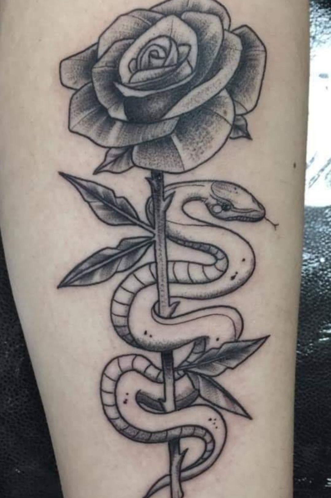 Snake and red rose tattoo located on the upper arm