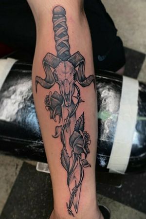 Dagger and ram skull, with dead roses and barbed wire.