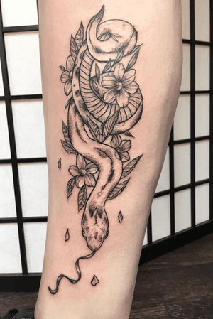 Snake and cherryblossom floral design on the leg. Blackwork andwhite highlight. Dotwork and whipshading. 