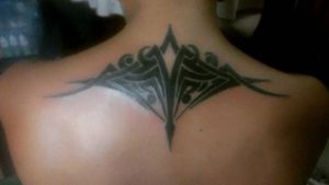 Tatuaje tribal en la parte alta de la espalda, diseño propio, color negro Tribal tattoo on the upper back, own design, black color