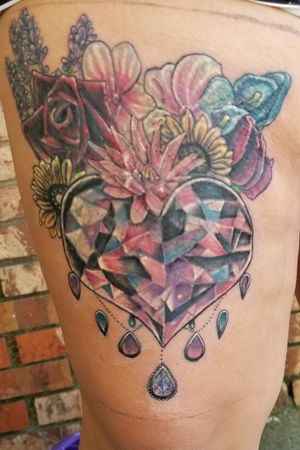 Massive cover up tattoo of a faceted heart shaped gem with a bouquet of flowers behind . The cover up was over a poorly placed and executed black and grey butterfly.