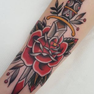 Tatuaje de rosa tradicional de Nikko Tattoos from Berlin Ink #NikkoTattoos #BerlinInk #traditional rose tattoo #traditional rose #rose tattoo #traditional tattoo #traditional #flower #flowers #plant #color # dagger #sword