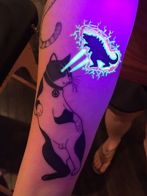 UV Ink Tattoo by Noil Culture #NoilCulture #uvinktattoo #uvink #uvtattoo #ultraviolet #ultraviolettattoo #uv #cat #smileyface #funny #godzilla #illustrative #arm