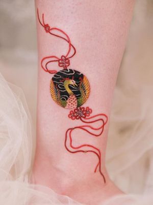 Phoenix inscribed pendant with red knots and strings on the ankle #tattoo #norigaetattoo #fantattoo #peonytattoo #colortattoo #flowertattoo #tattooistsion