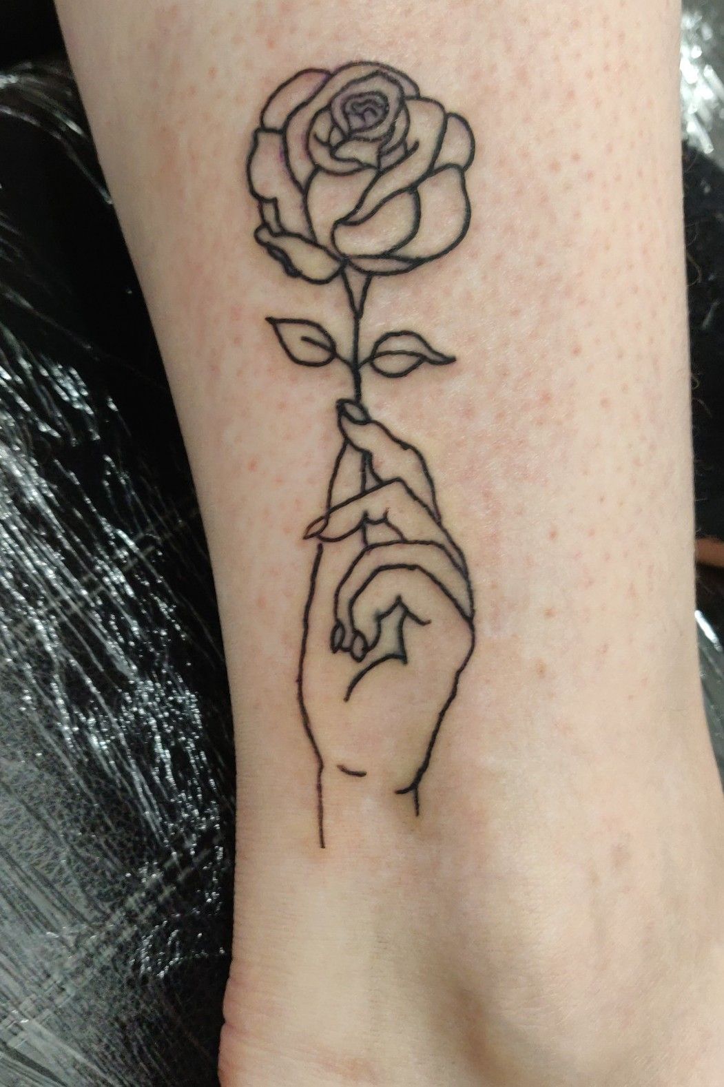 Hand holding flower tattoo by Gio Luca TattooNOW