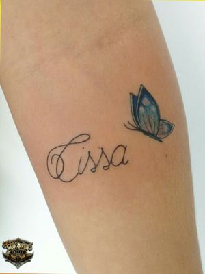 Tatuagem Fine Line em homenagem a alguém especial com uma borboleta em azul dando um toque suave a tatuagem em perfeita harmonia com o nome