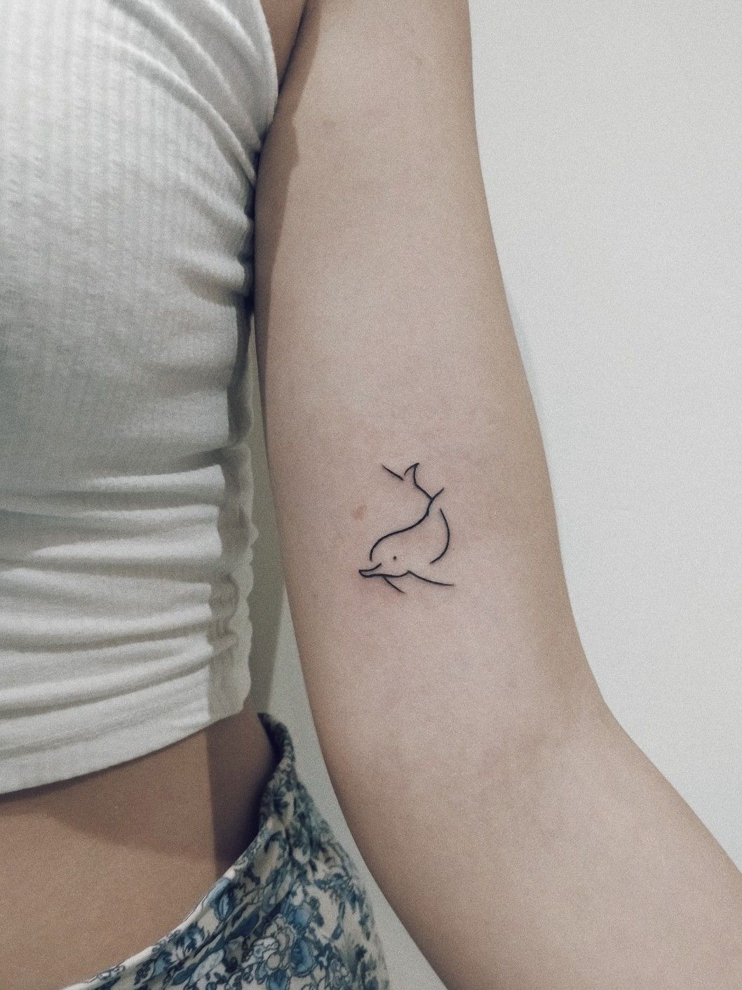 Fine line dolphin tattoo located on the ankle
