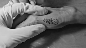 Tatuaje de Unalome en el proximal de la mano